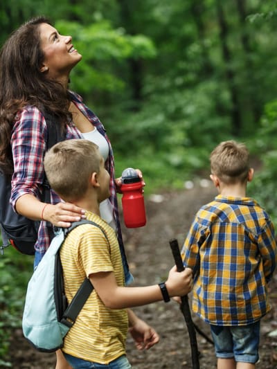a mom roadschooling her kids in a version of RV homeschooling by hiking in the woods for science class